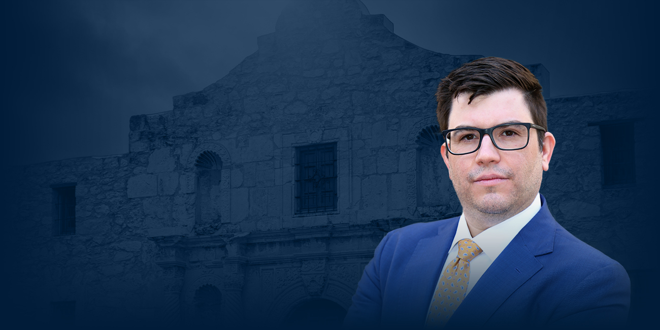 Daniel De La Garza with a background featuring a photograph of an old building with a blue filter, next to him the De La Garza Criminal Defense, PLLC logo.