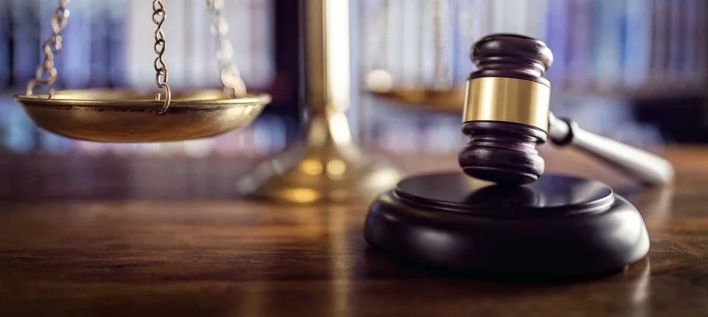 Judge's gavel and the scales of justice with books belonging to a criminal defense lawyer in San Antonio seen in the background. 